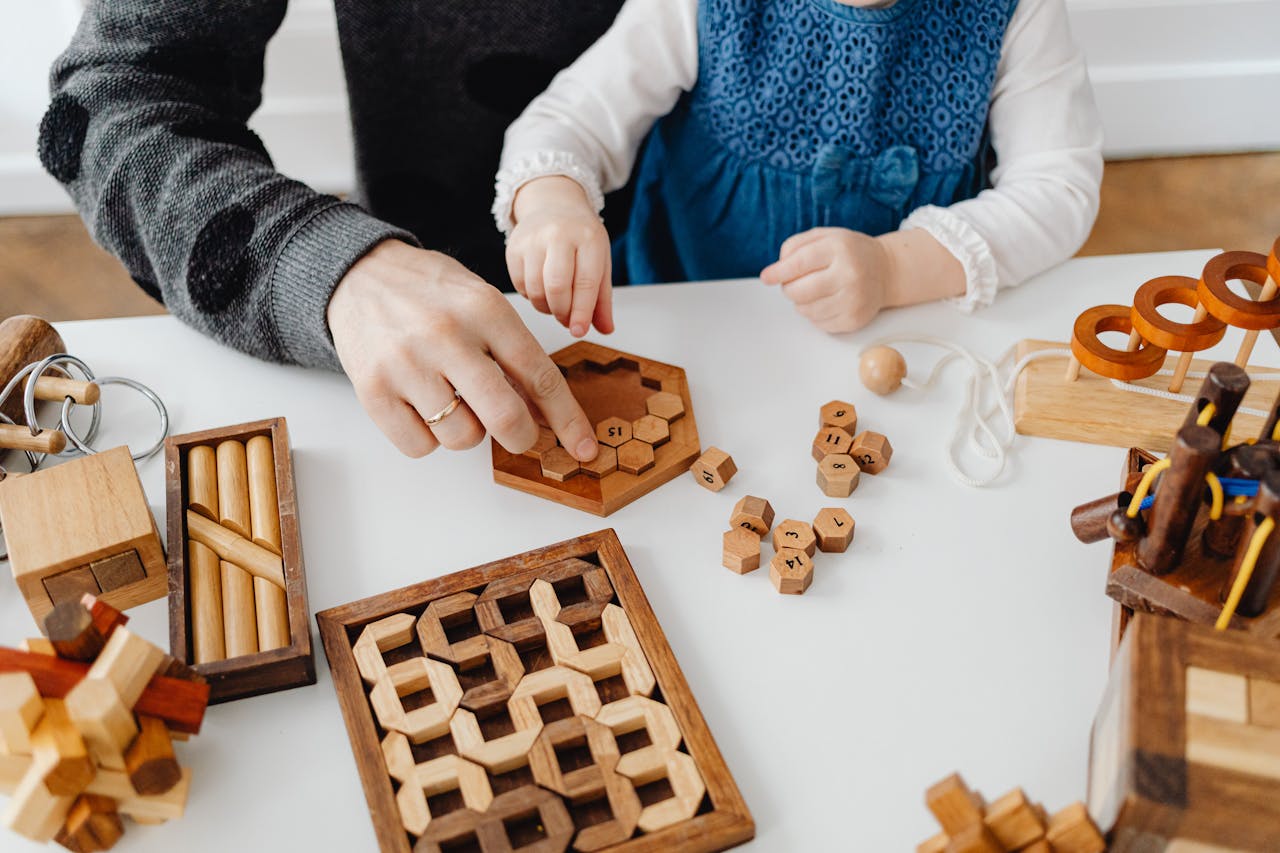 A father and child engaging with wooden educational toys at a table indoors.